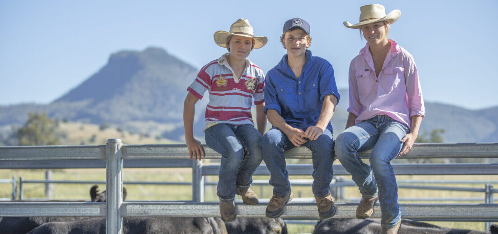 Bike Territory Family Three young individuals sitting on top of a cattle yard fence.