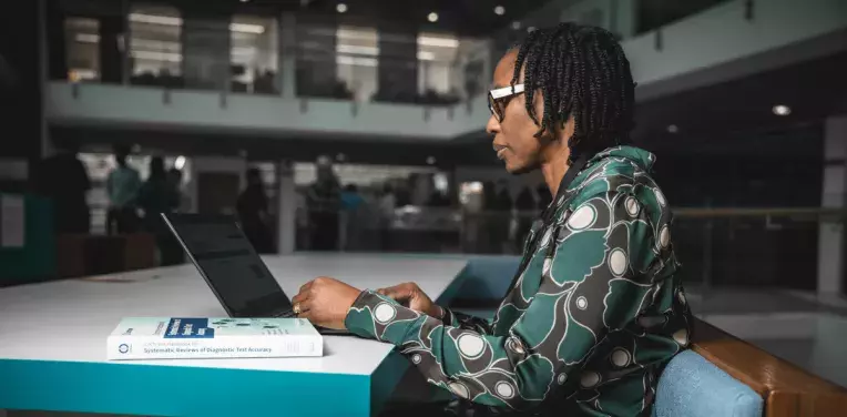 Cochrane researcher sitting at laptop working 