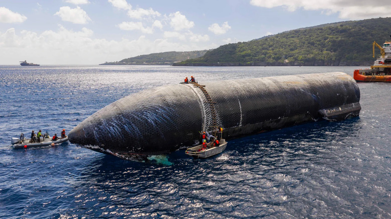The upper stage of SpaceX's Starship 40 floating in the water. Workers surround it with a ladder draped over it.
