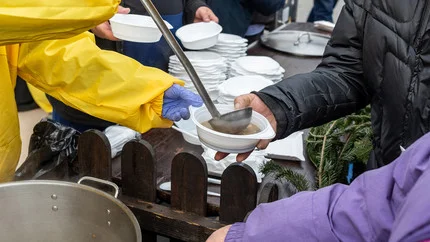 Helfende Menschen geben Suppe aus.