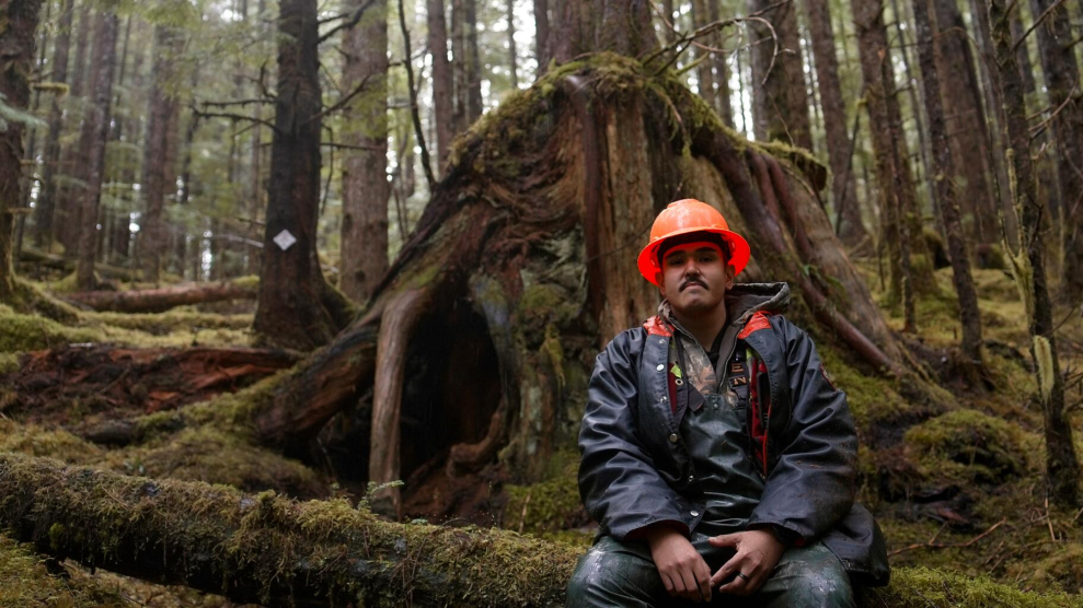 Elijah Washington, a Haida member and stewardship technician with the Council of the Haida Nation, sits in front of a bear den he and his crew created from an old stump this summer, which they will monitor through winter.